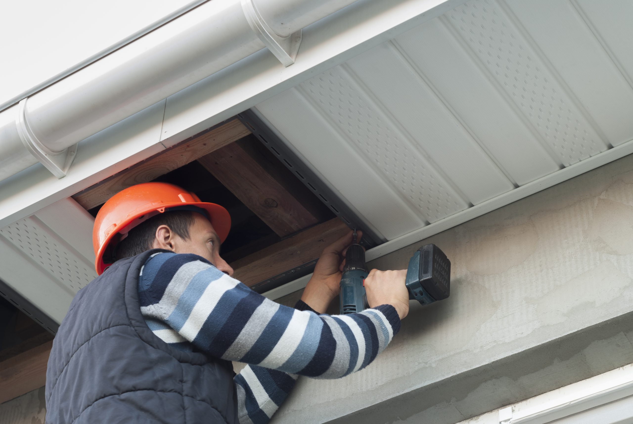Travailleur installant des soffites pour protéger la toiture d’une maison
