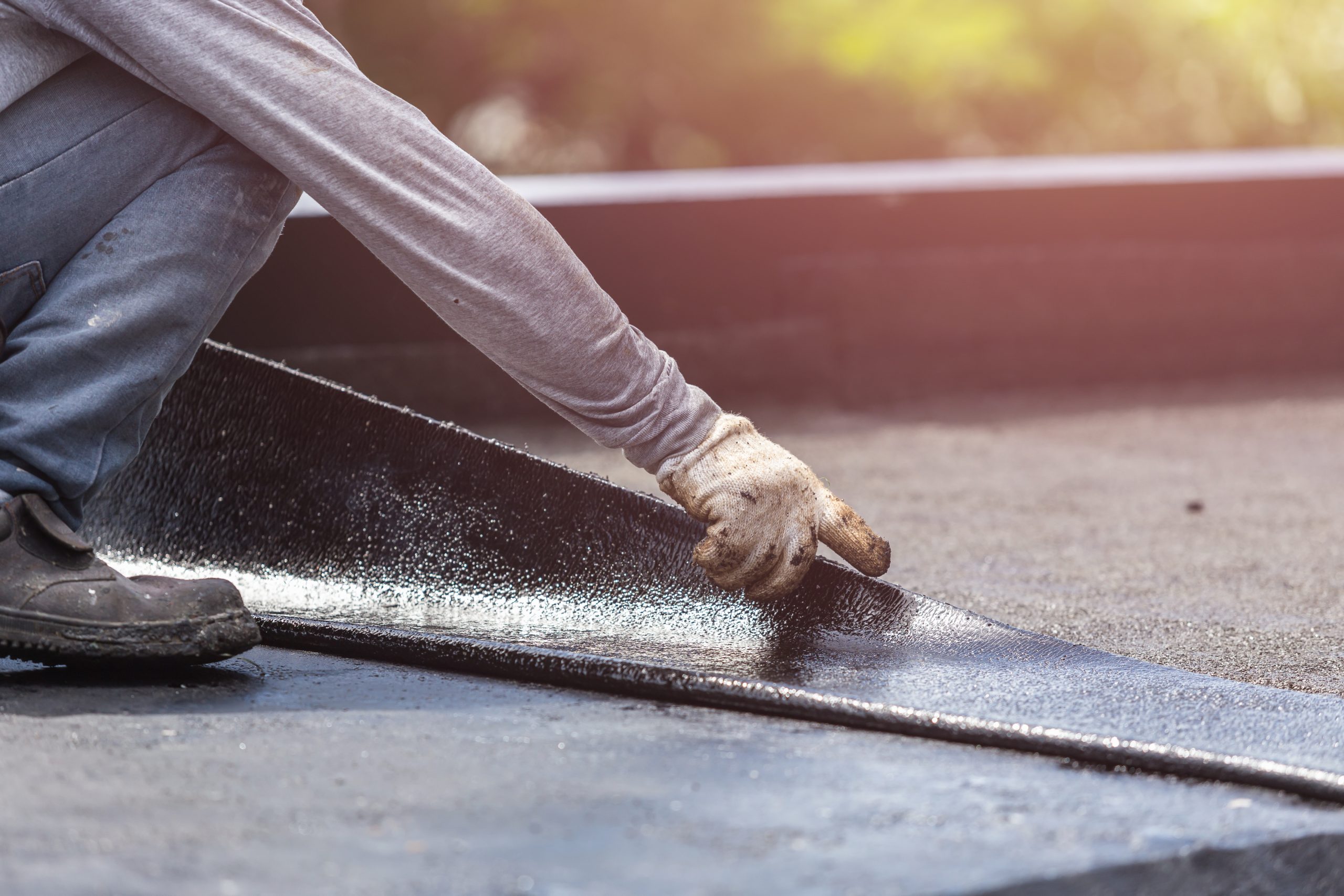 A roofer installs an elastomeric membrane on a flat roof