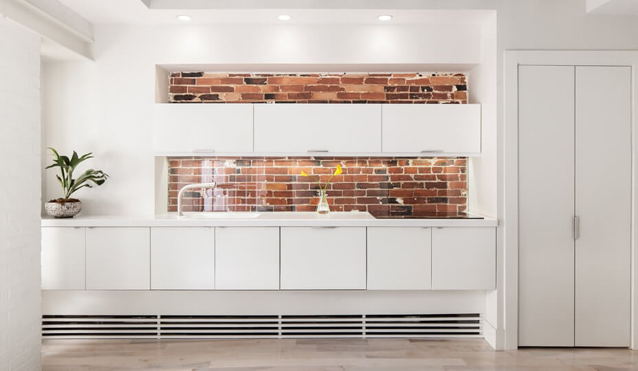 white kitchen with a brick wall backsplash