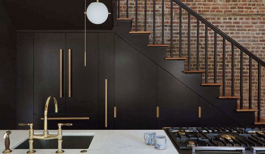 small black and gold kitchen next to a staircase