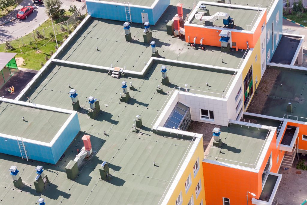 Vue aérienne d’un toit plat avec membrane élastomère sur un immeuble moderne bleu, jaune et orange