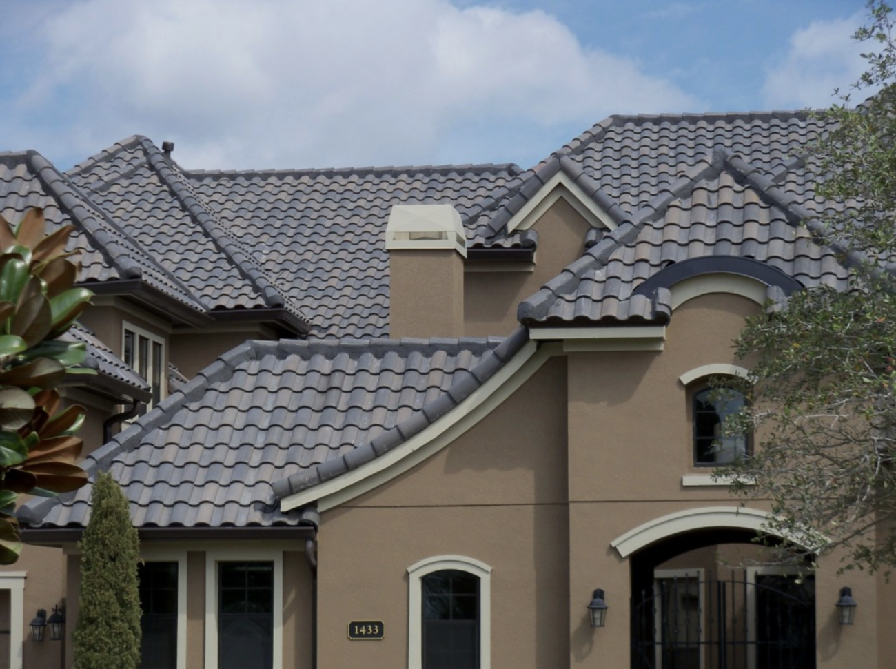 Luxurious residence with taupe-coloured walls, featuring a gabled roof covered with grey clay tiles