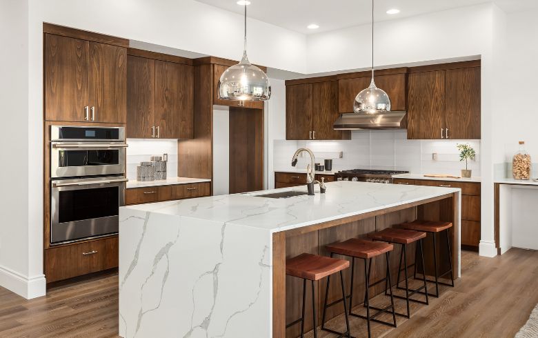 two-tone kitchen with marble island and brown cabinets