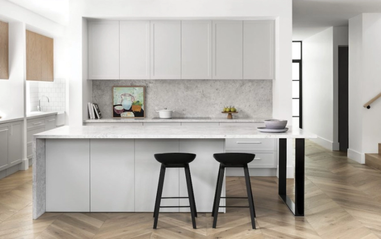 modern kitchen with white cabinets, marble island and black stools