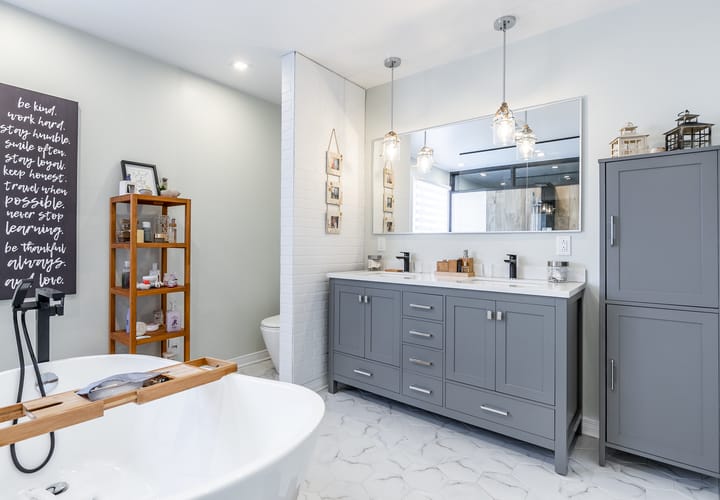 A large grey double vanity with many drawers is next to a tall grey storage cabinet.