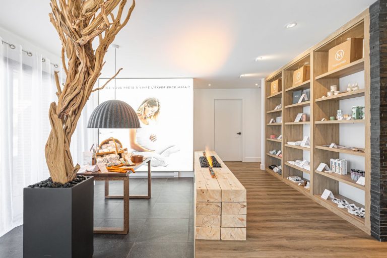 Boutique prénatale zen avec présentoirs et étagères en bois, foyer central moderne et branche d'arbre décoratif