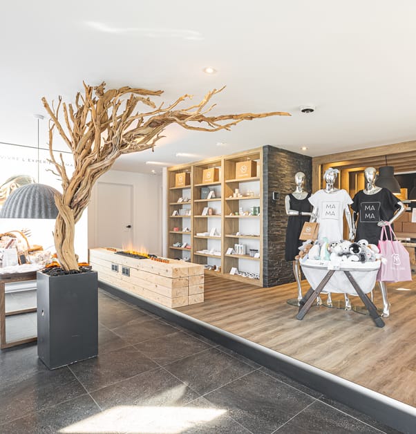 Espace boutique d'une clinique prénatale zen aux accents de bois avec arbre décoratif et présentoirs