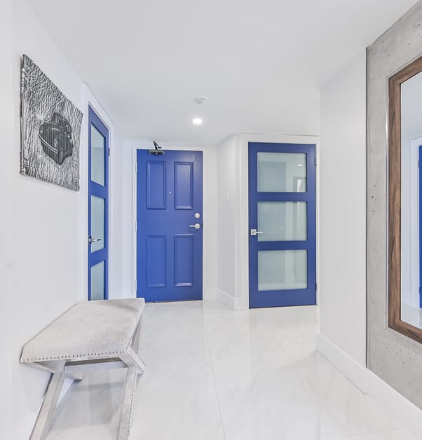 Condo hallway with white stone floors, white walls, and blue doors.