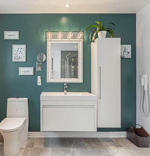 salle de bain avec un mur d'accent sarcelle, toilette et vanité flottante blanche