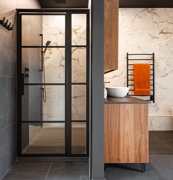 Modern bathroom with a marble backsplash, black accents, and a walk-in shower