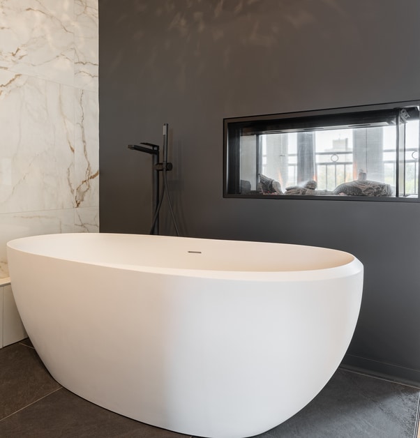 Salle de bains avec dosseret en marbre, foyer et baignoire autoportante.