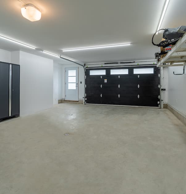 garage renovation with overhead lights, black door, and storage