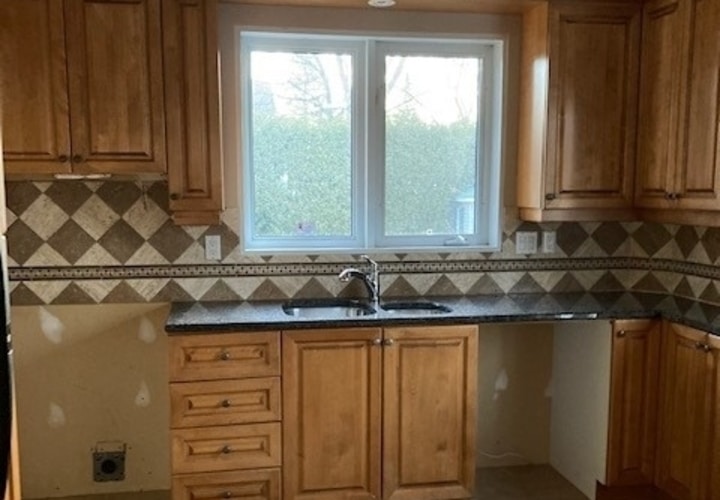 Old kitchen with dated wooden cabinets and checkered backsplash