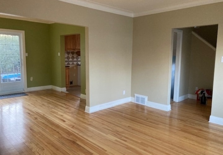 Room with hardwood flooring and beige and green walls