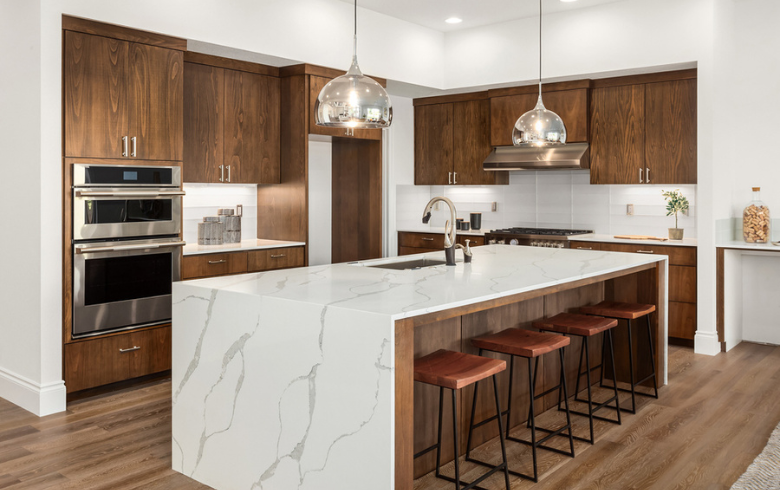 L-shape kitchen layout with brown wood vabinets and marble kitchen island