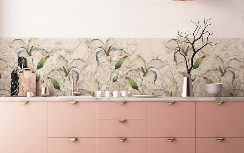 cuisine rose avec des meubles gris-rose, des poignées dorées et du papier peint à fleurs pour le dosseret
