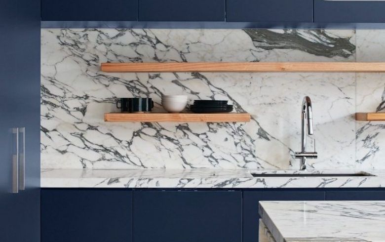 kitchen with marble slab backsplash, blue cabinets and wooden shelves