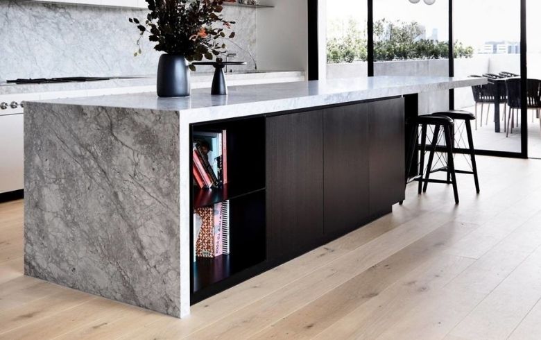 kitchen island with marble waterfall countertop and black cabinets
