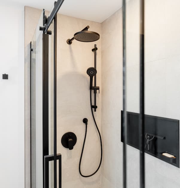 Modern walk-in shower with stone tiles and black accents