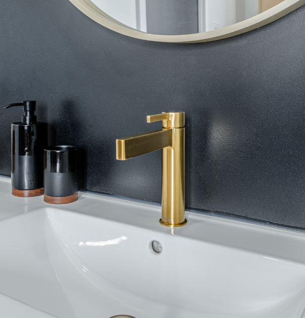 Gold bathroom faucet with white sink and black accessories
