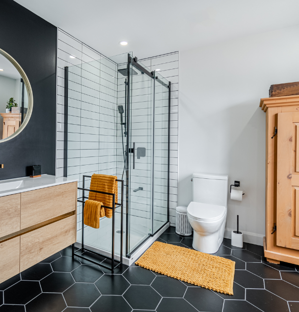 Salle de bain moderne rénovée avec carreaux hexagonaux noirs, douche blanche et meuble-lavabo en bois