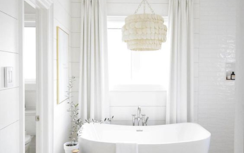textured chandelier above freestanding tub in white bathroom