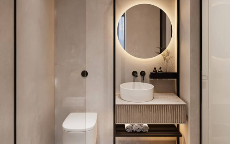 Petite salle de bains avec un meuble-lavabo personnalisé comprenant un miroir rond à DEL à côté de la toilette