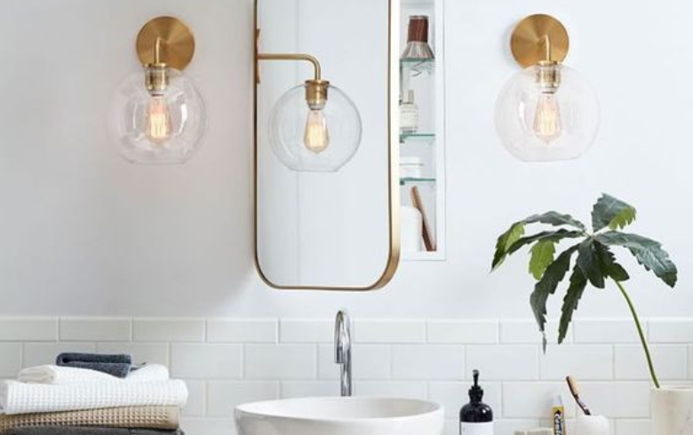 suspended gold wall sconces next to medicine cabinet mirror