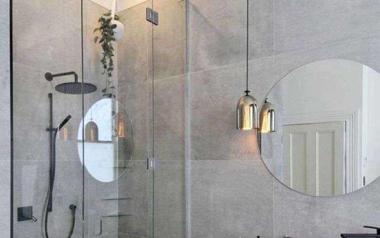 Grey toned bathroom with walk-in shower, round mirror and suspended gold light fixture