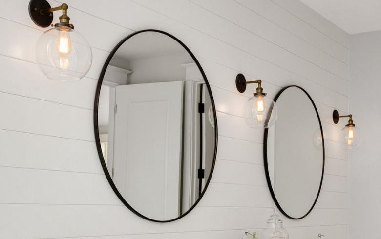 Two round black-trimmed mirrors with round wall sconces on each side