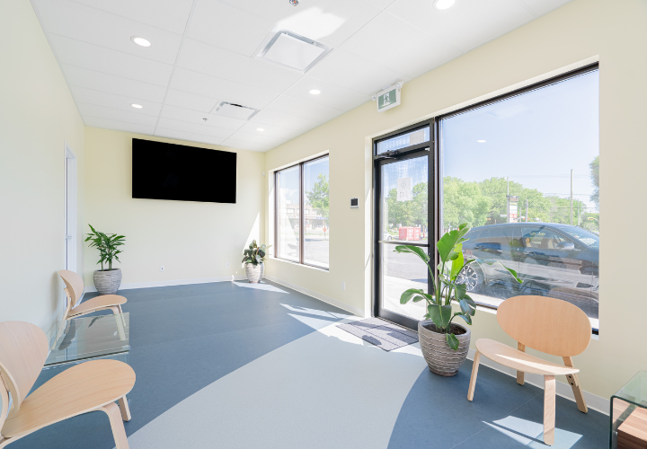 clinic renovation featuring a bright waiting area with wooden chairs, a TV, and pot lights