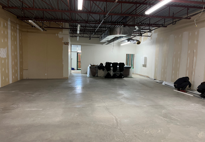Commercial empty space with oncrete floors, bare walls, and exposed fluorescent lights