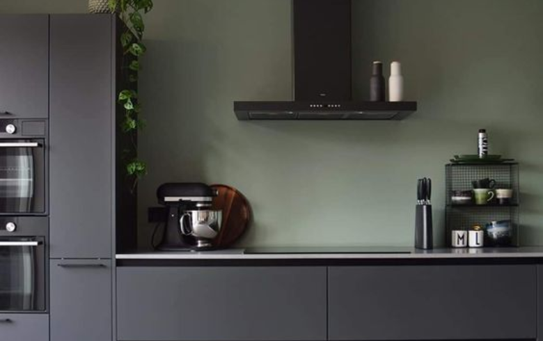black kitchen with sage green paint as a backsplash