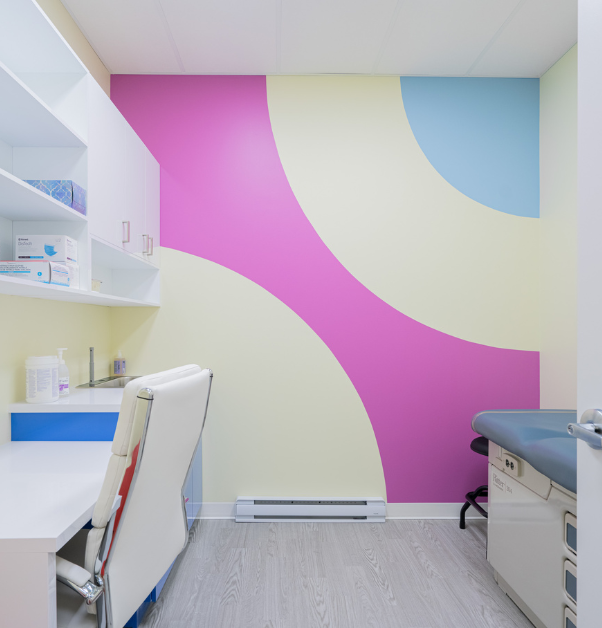Salle d'examen de clinique médicale avec armoires blanches et mur d'accent bleu et violet