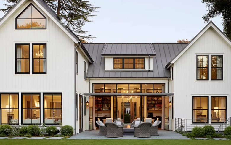 Maison style farmhouse avec revêtement extérieur blanc et toit en aluminium gris