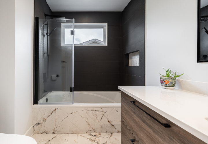 Salle de bain moderne rénovée avec bain-douche, céramique murale noire mat, planchers en céramique avec fini effet marbre brun et vanité moderne