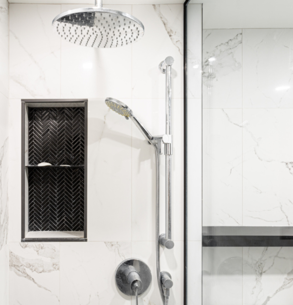 Renovated walk-in shower with white marbled ceramic tiles, silver showerhead, and faucets