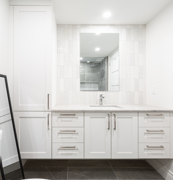Salle de bain rénovée avec vanité flottante, comptoir en quartz blanc, dosseret en carreaux grisâtres et plancher en céramique foncé