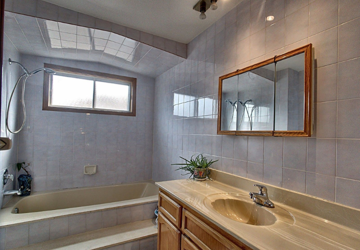 Before renovation old fashioned bathroom with dull blue-grey ceramic tiles on walls