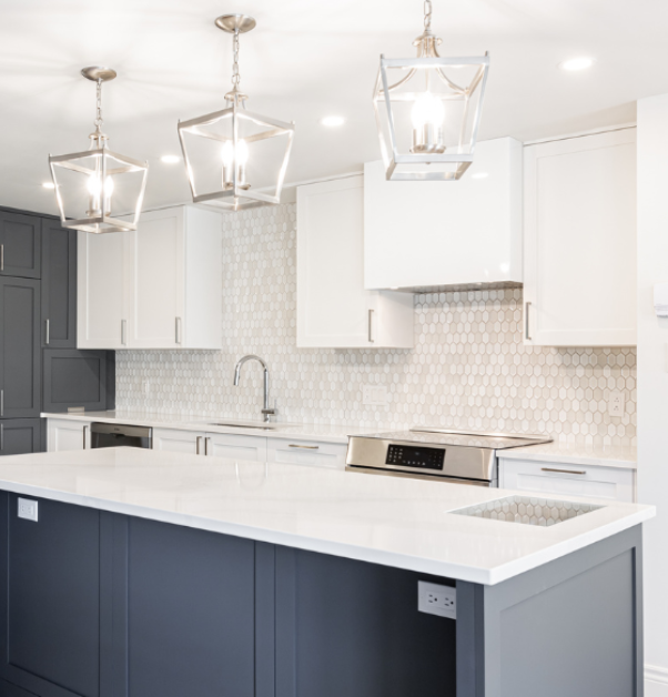Renovated kitchen with white quartz center island, dark grey cabinets, and pendant lighting