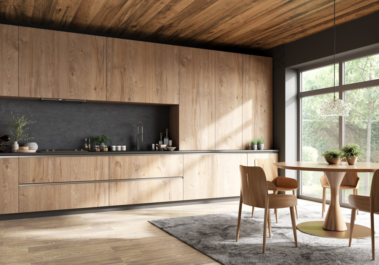 Design intérieur d’une cuisine minimaliste aux armoires en bois, avec table à manger ronde et chaises près d’une fenêtre