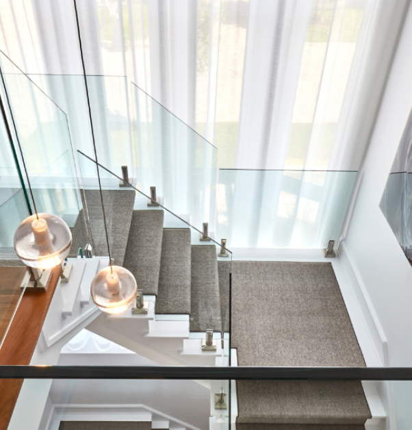 grand escalier avec tapis au milieu et rampes en verre dans un projet de rénovation multiple haut de gamme
