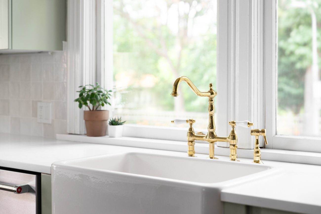 Gold-plated tap under kitchen window