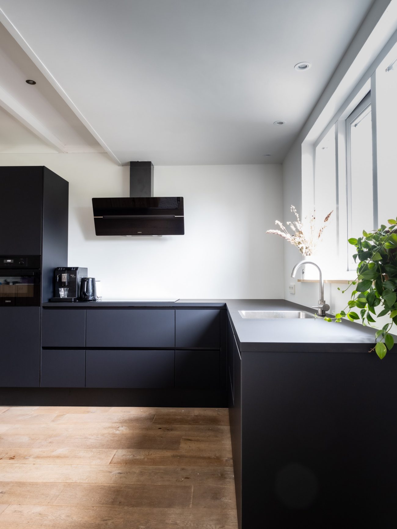 Interior kitchen with large black countertop, preparation area and sink under the window