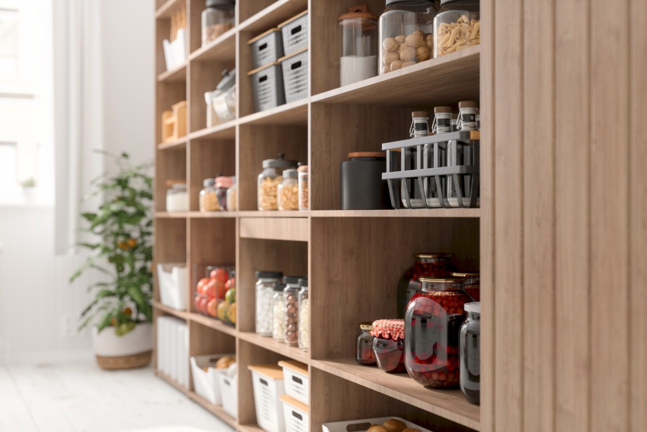 A variety of foodstuffs and jarred foods on the shelves of a large modern scullery