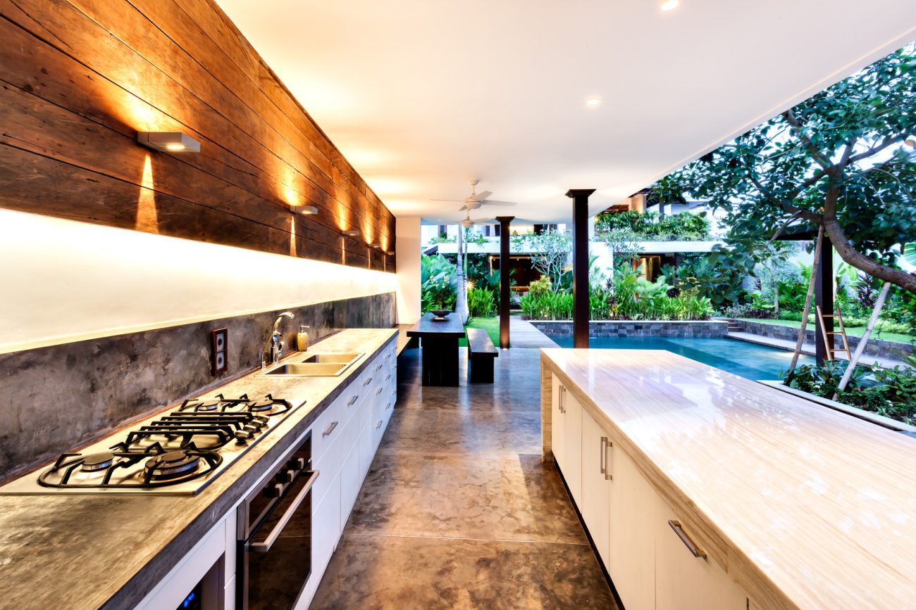 Luxurious outdoor kitchen with worktop, sink, barbecue, pendant lights and dining area