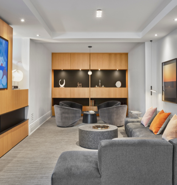 Salle de TV du sousol avec des teintes de bois jaunes et un foyer intégré dans un projet de rénovation multiple haut de gamme