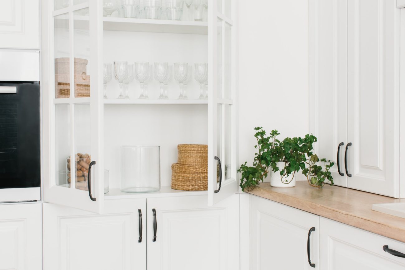 White glass cabinet with tableware on shelves, kitchen storage organization