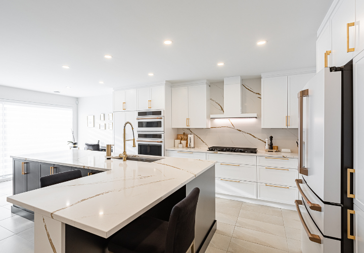 renovated kitchen with marble counter and white cabinets with gold handles