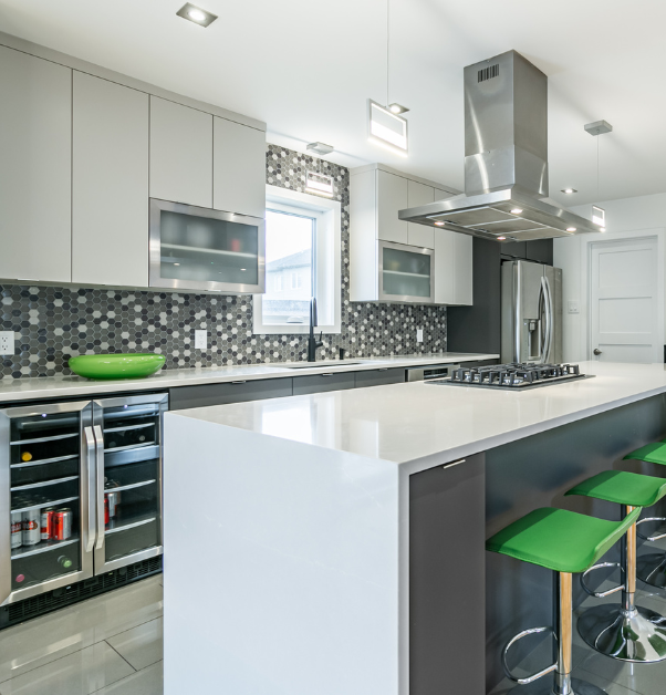 Modern kitchen renovation with center island with waterfall quartz countertop, green stools and hexagonal mosaic backsplash in modern kitchen makeover